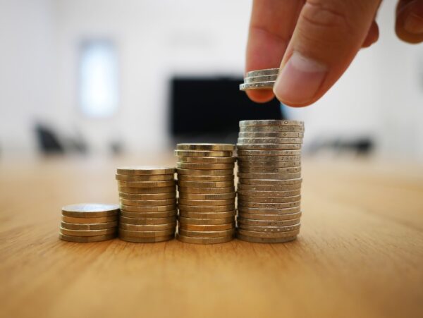 GenXers Need This Guide To Cut Debt & Up Retirement Savings : Image shows a person stacking increasingly larger piles of coins